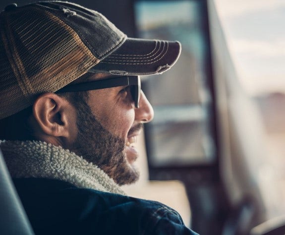 Smiling truck driver inside Volvo VNL showcasing Remote Diagnostics.