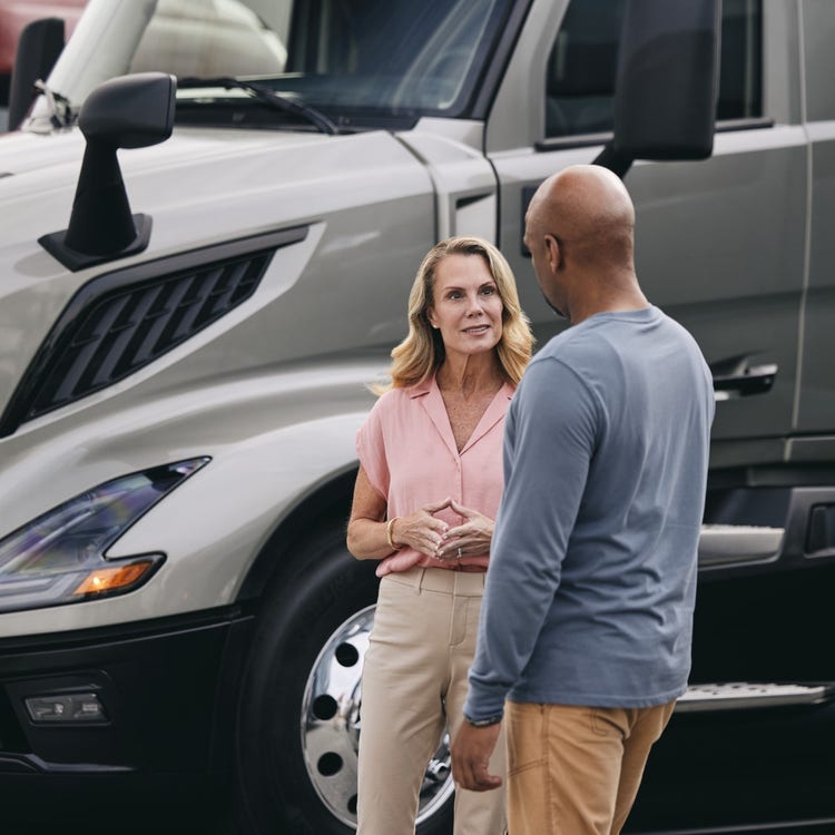 Two people discussing beside a Volvo VNL truck, highlighting adaptive maintenance