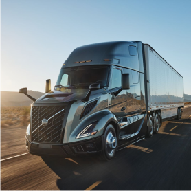 Volvo VNL Coastal Mist colored truck driving on a highway at sunrise