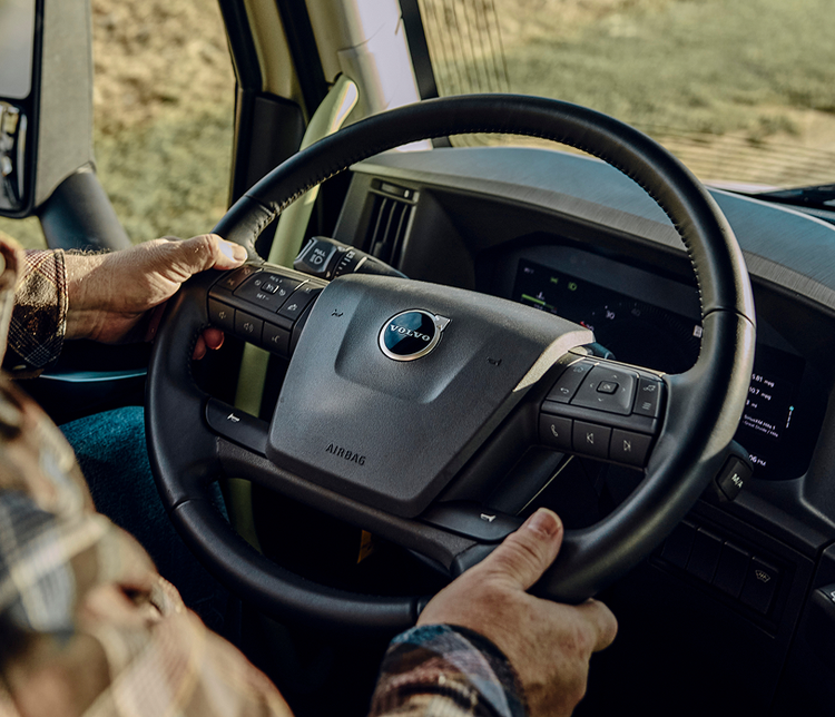 A close up view of the steering wheel of the Volvo VNX with the drivers hands on the wheel.