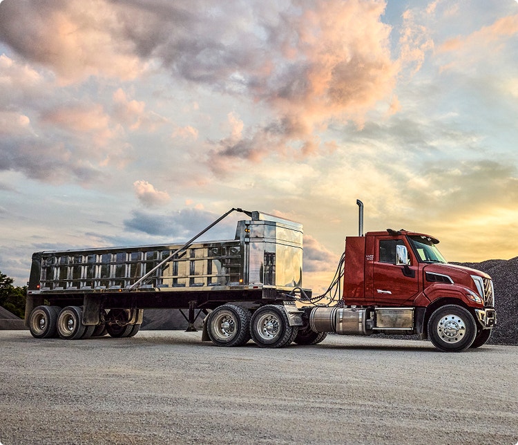 Side view of a red color Volvo VNX logging truck.