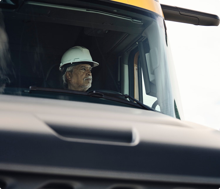 A closeup of a driver behind the wheel of a Volvo VNX.