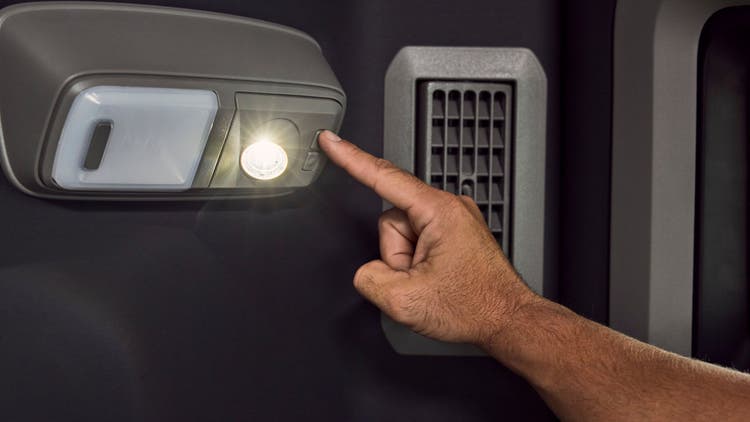 A finger reaching a switch next to a light that's already shining.