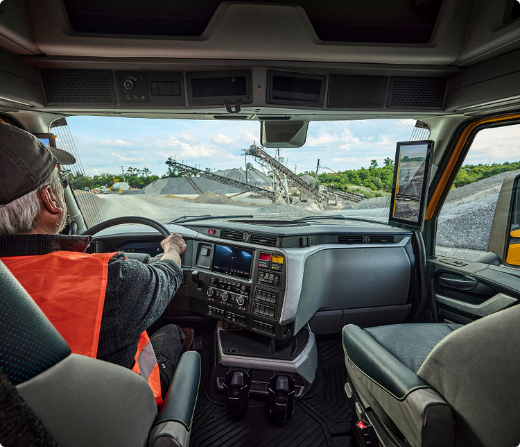 A view from behind the driver driving a VNX to a construction site.