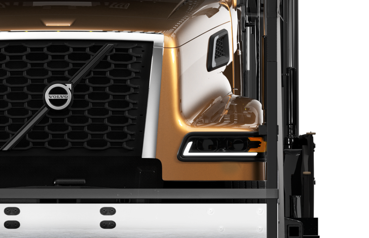 Close-up of the front grille and LED headlight of a gold Volvo VAH truck, showcasing its sleek design and bold details