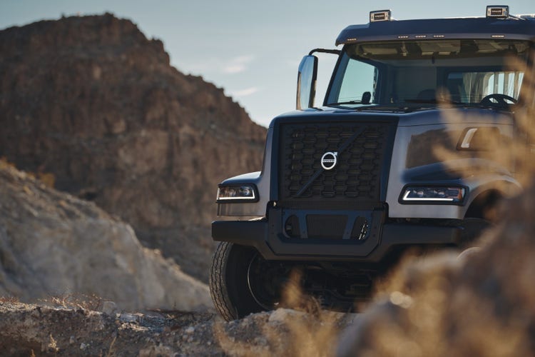 Front view of a Volvo VHD truck against a rugged, rocky landscape, emphasizing its bold grille and durable design for challenging terrains.