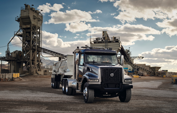 Volvo VHD truck parked at an industrial site with heavy machinery in the background, highlighting its capability for demanding construction and hauling tasks.