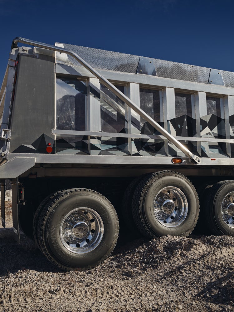 Close-up of the polished rear wheels and sturdy aluminum dump body of a Volvo VHD truck.