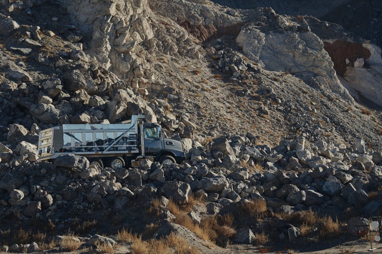 A Volvo VHD dump truck navigating a rocky, uneven terrain in a quarry.