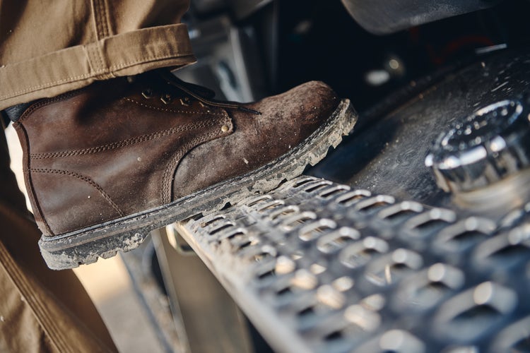 Close-up of a worker's boot stepping onto the durable, textured metal step of a Volvo VHD truck, highlighting ease of access