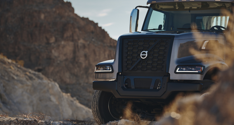 Front view of a Volvo VHD truck against a rugged, rocky landscape, emphasizing its bold grille and durable design for challenging terrains.