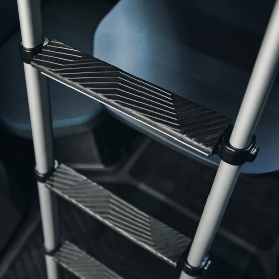 A foldable ladder with textured black steps inside a Volvo VNL sleeper cab
