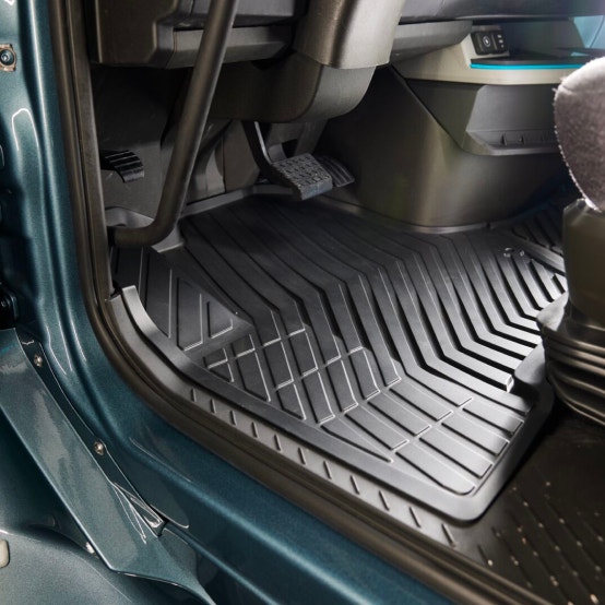 A Volvo VNL cab's driver-side floor, featuring durable, textured black floor mats for easy cleaning