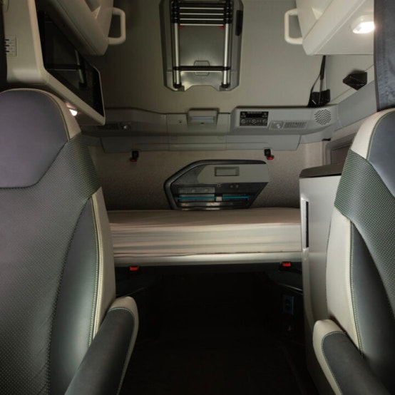 Volvo VNL sleeper cab with a lower bunk, integrated storage compartments, and overhead lighting for driver comfort.