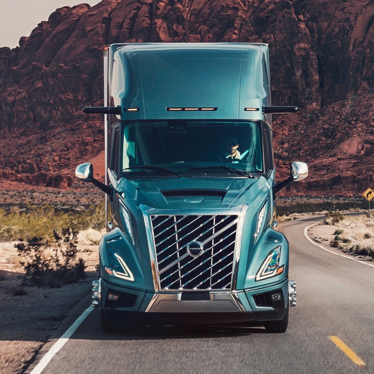 Front view of a Volvo VNL truck traveling through a scenic desert landscape, with bold grille and headlights standing out