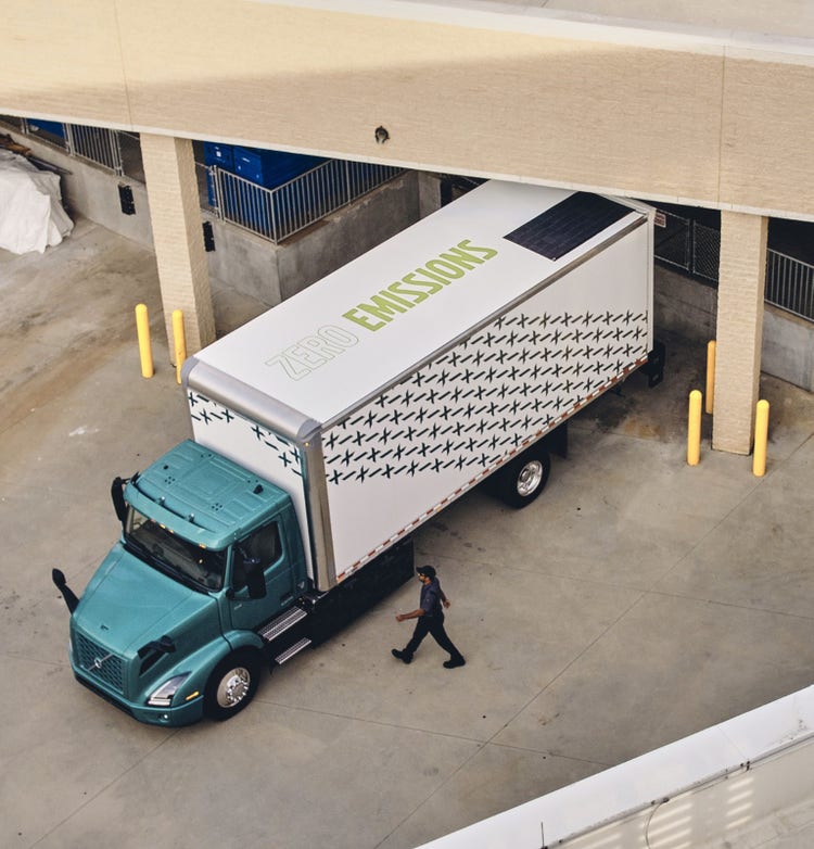 Overhead view of a Volvo VNR Electric truck parked at a loading dock, showcasing its 'Zero Emissions' branding.
