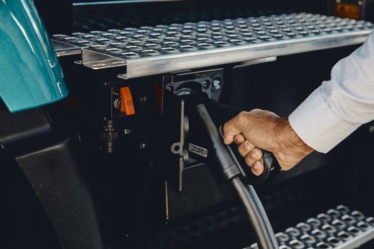 Close-up of a person plugging a charging cable into a Volvo VNR Electric truck