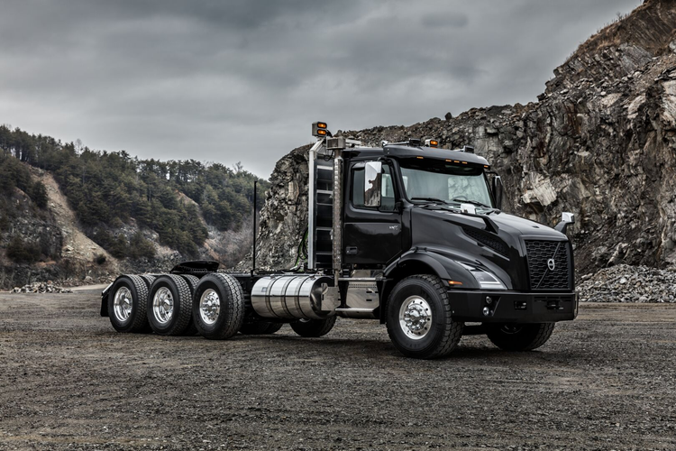 A black Volvo VNX truck parked at a rugged worksite, setting standard for heavy haul.