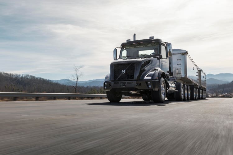 A black Volvo VNX truck hauling a heavy-duty trailer on a highway, designed for maximum performance and reliability in demanding transport jobs.
