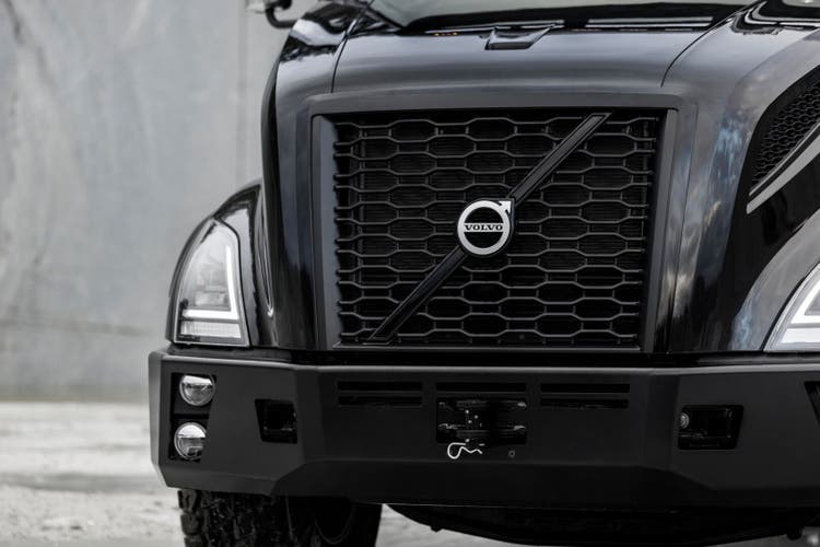 Close-up of the bold grille and LED headlights of a black Volvo VNX truck